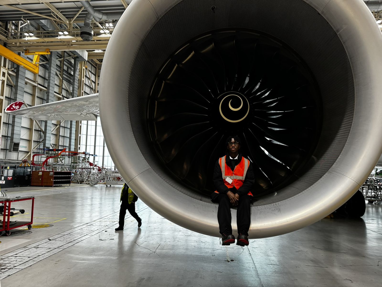 Kobi sitting inside the engine intake of a Virgin Atlantic aircraft in a hangar