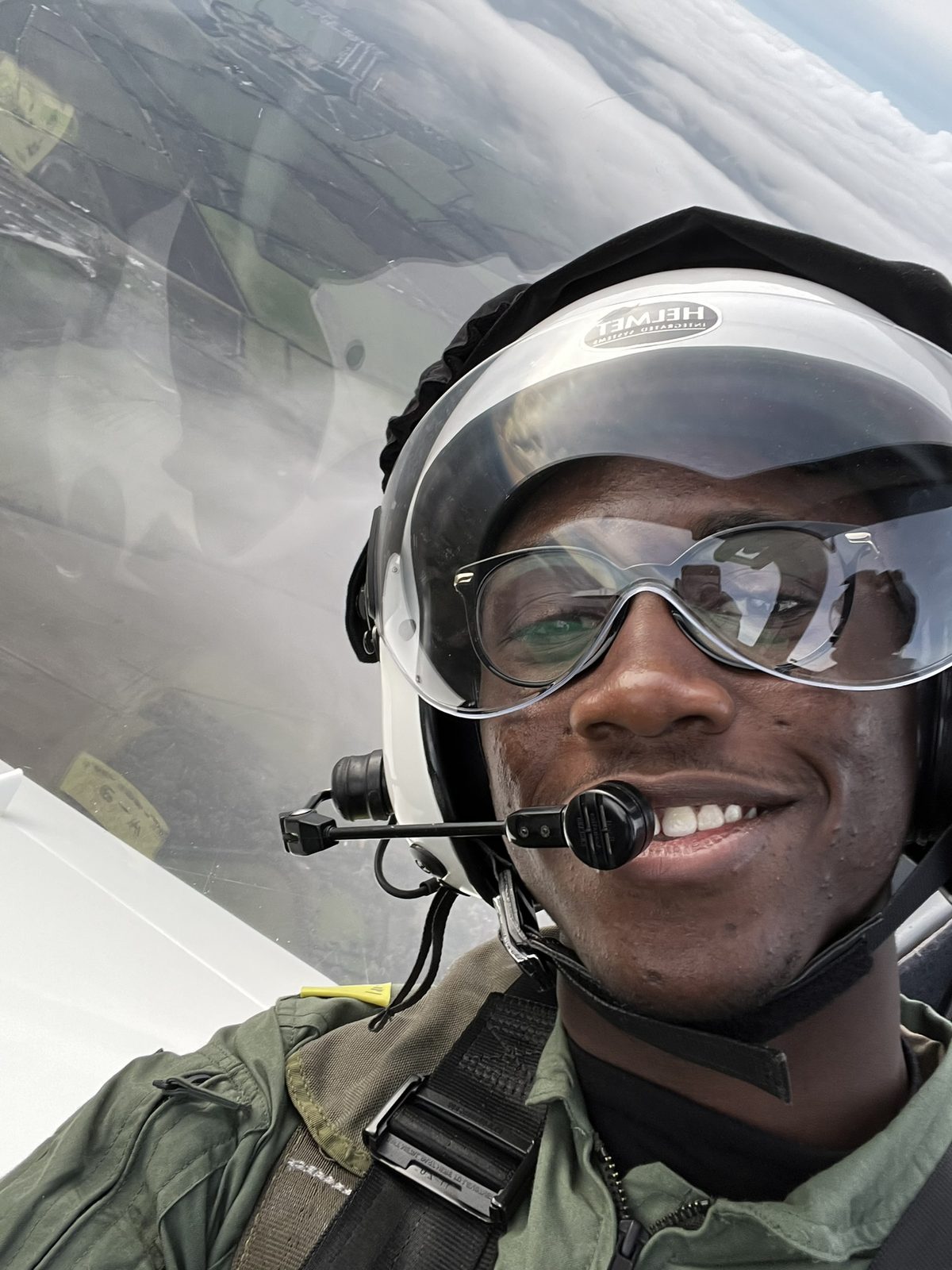 Kobi smiling in a flying helmet and goggles in the cockpit of a Grob G103 Twin Astir