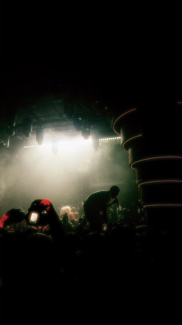 A performer leaning into the crowd under hazy stage lights