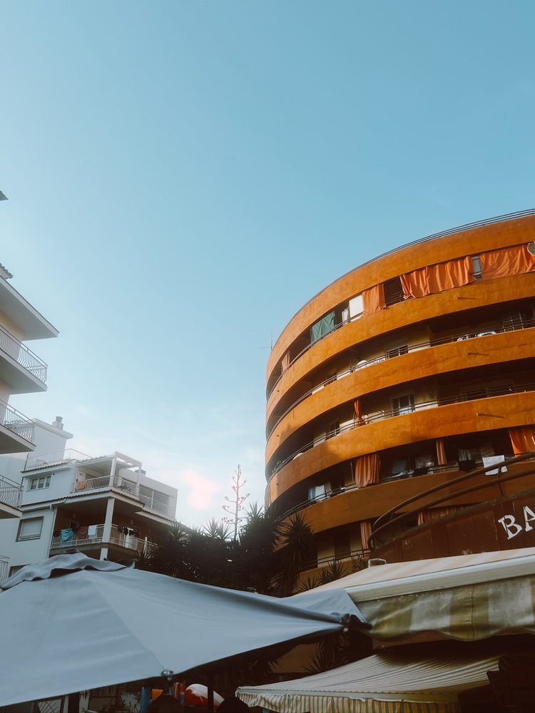 A curved orange apartment building against a blue sky