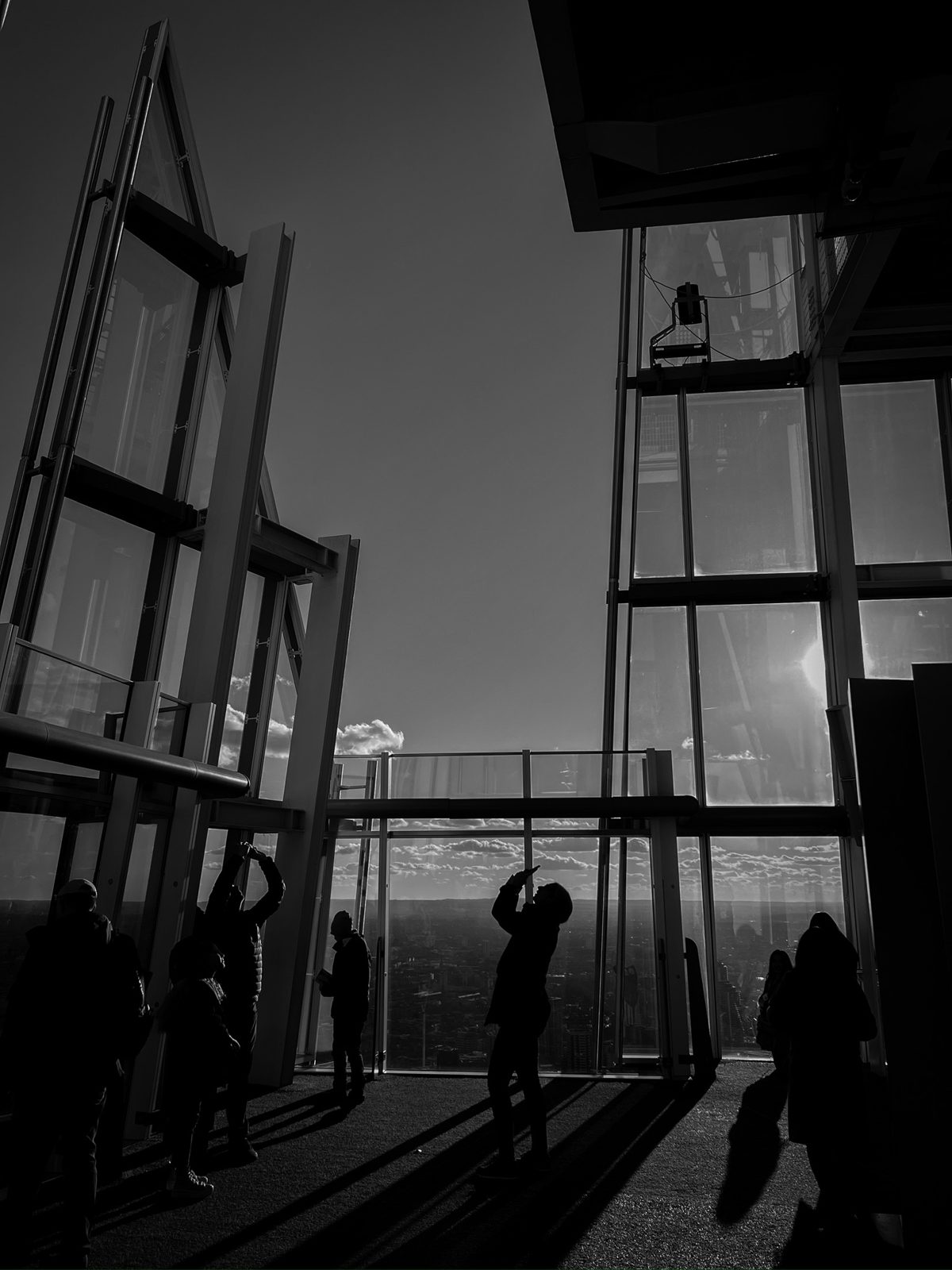 Black and white shot of visitors silhouetted against the glass at the top of the Shard